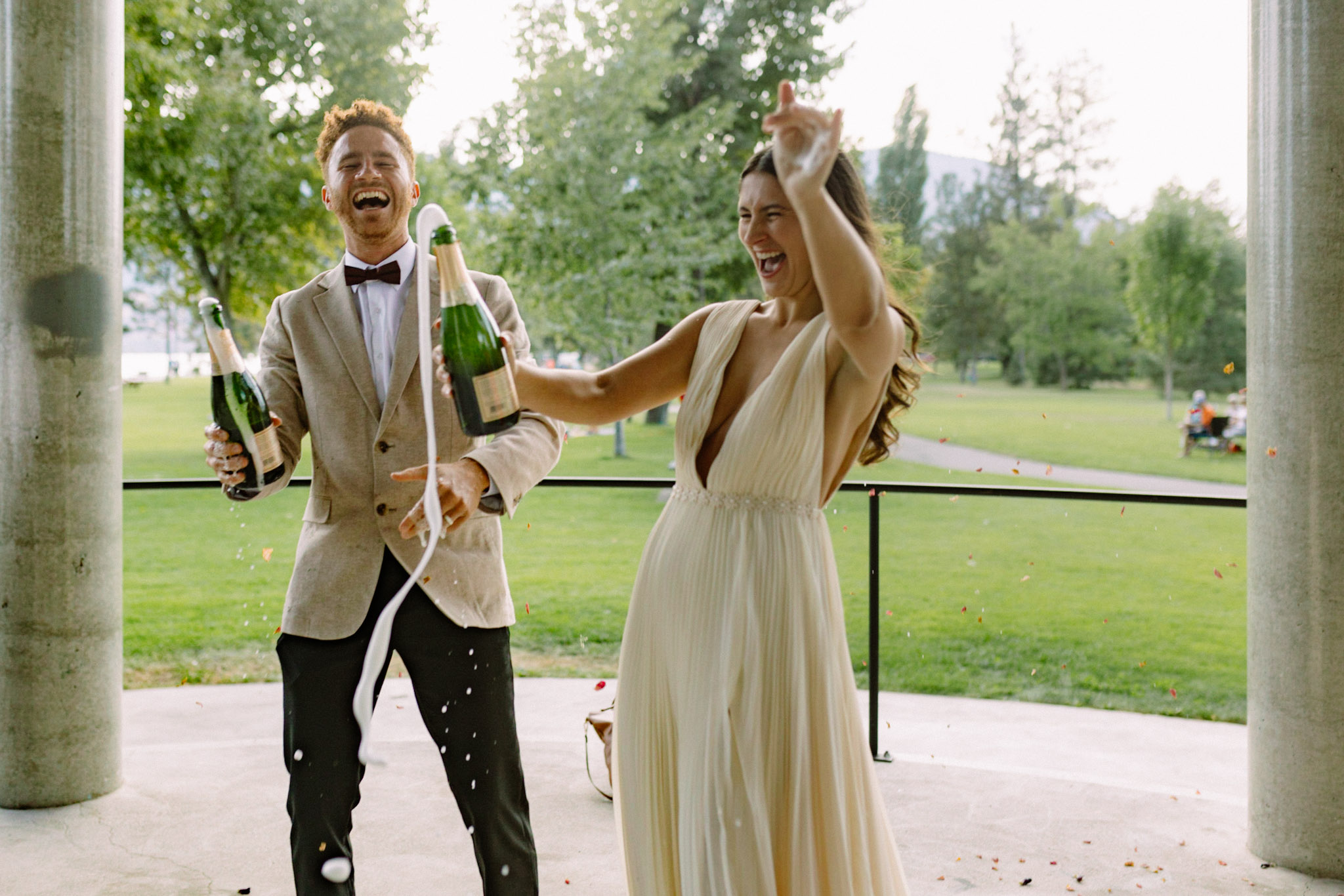 couple celebrates with a champagne spray after getting married in the gazebo at skaha lake in penticton bc